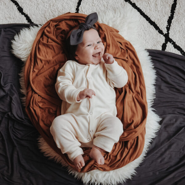 Auf diesem Foto siehst Du ein lachendes Baby, das ein Haarband in dunkelgrau trägt.