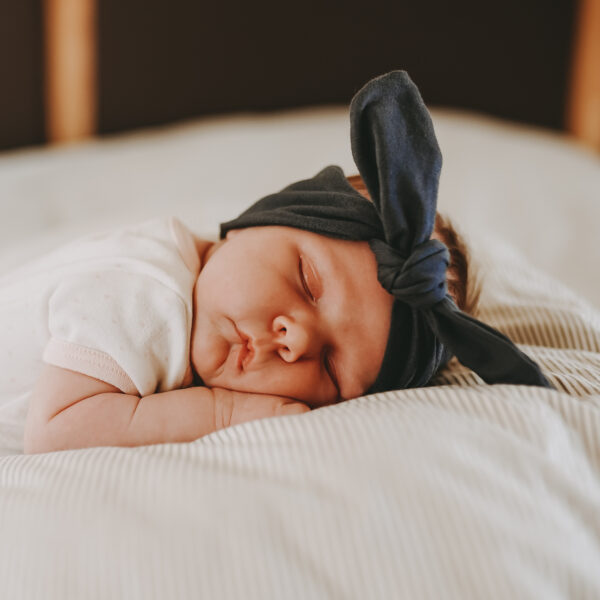 Auf diesem Foto siehst du ein schlafendes Baby, das ein Haarband blau von Little Wombat trägt.