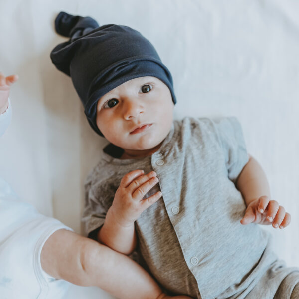 Auf diesem Foto siehst du ein Baby mit unserer geknuteten "Babymütze dunkelblau"