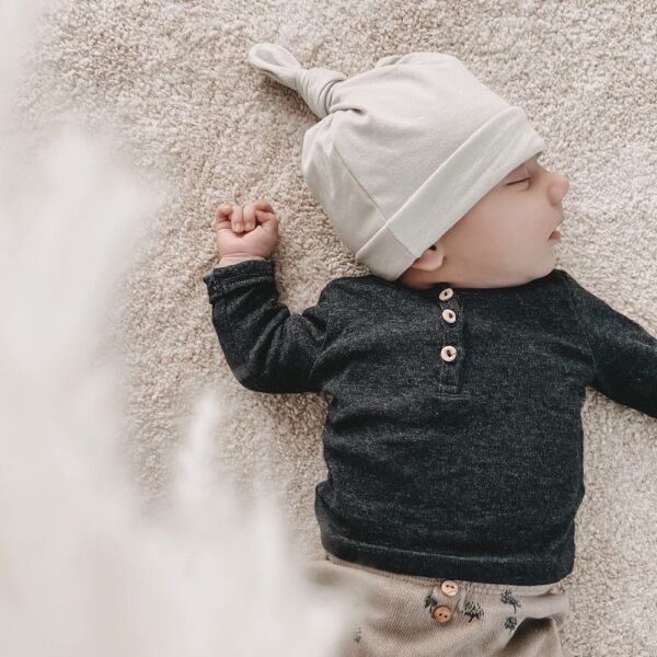 Auf diesem Bild siehst Du ein Baby, das unsere geknotete "Babymütze grau" trägt
