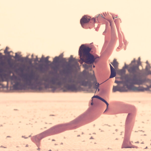 Auf diesem Foto siehst Du eine Mama, die mit ihrem Kleinkind Yoga macht