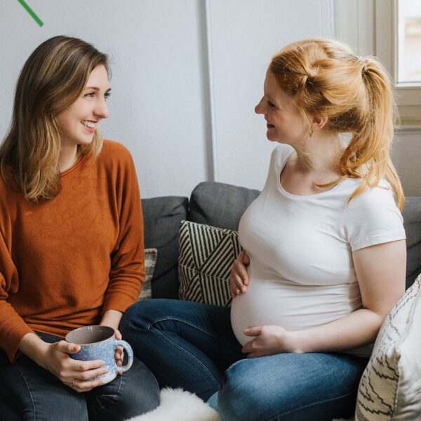 Auf diesem Foto siehst du eine schwangere Frau im Gespräch mit ihrer Doula. Es geht um die Betreuungsformen in der Schwangerschaft