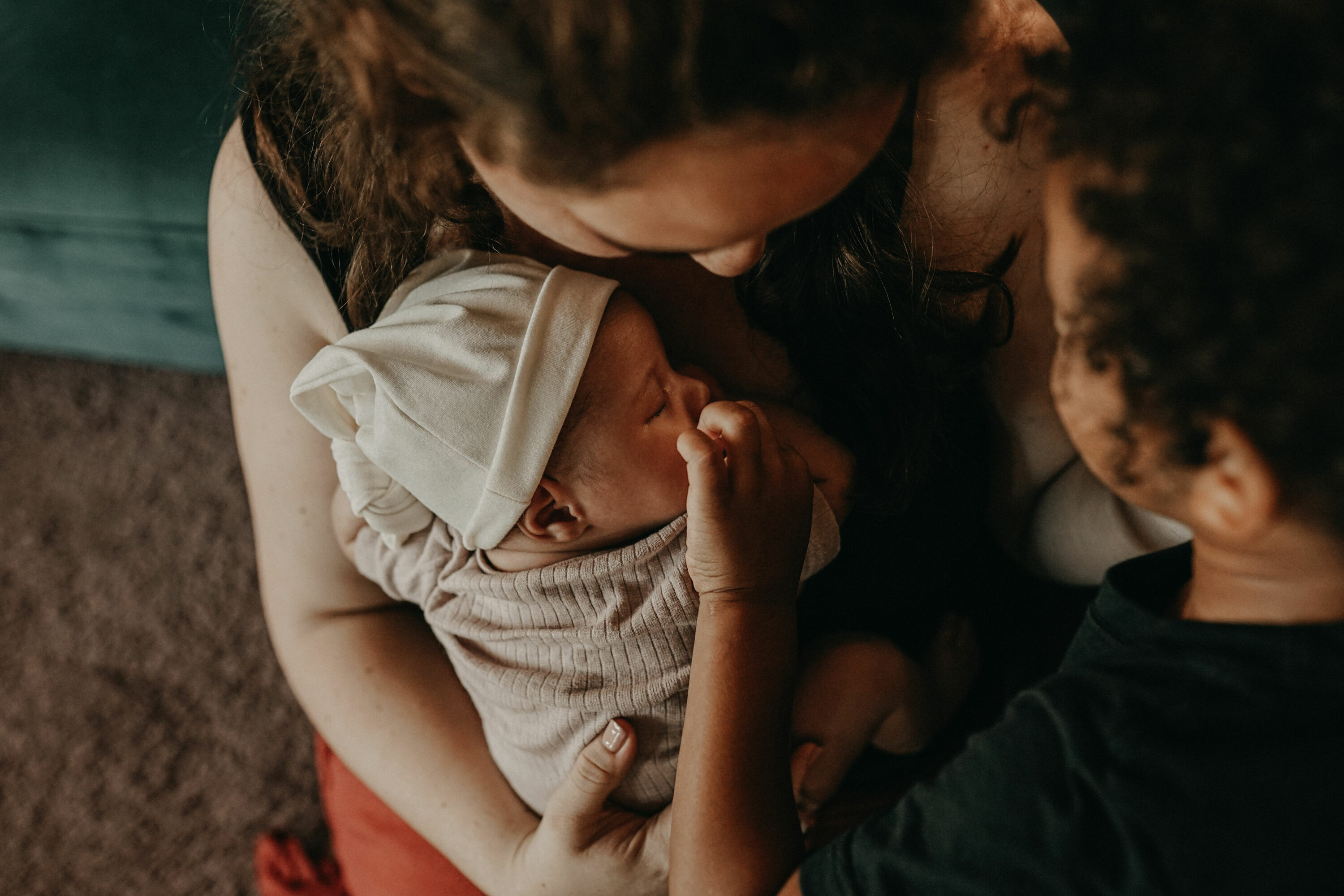 Auf diesem Foto siehst Du eine Mama im wochenbett mit ihren Geschwisterkindern