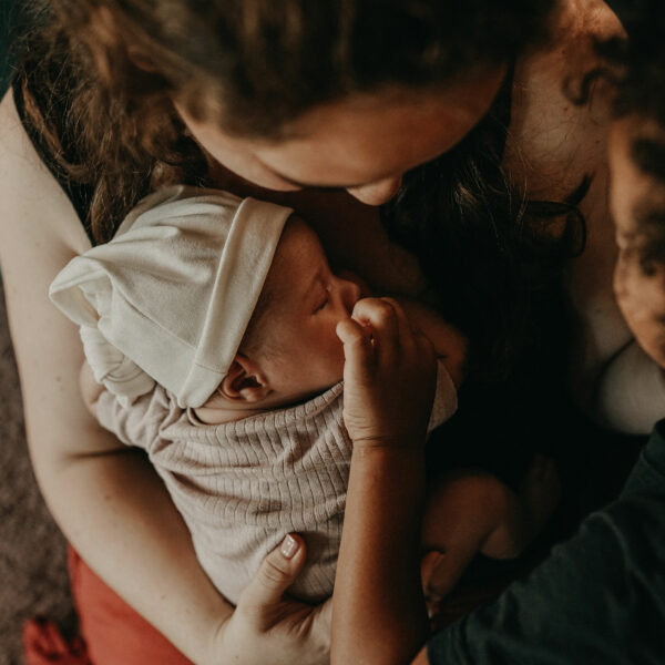 Auf diesem Foto siehst Du eine Mama im wochenbett mit ihren Geschwisterkindern